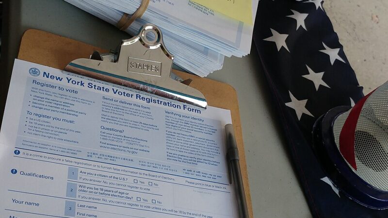 Voter registration forms and clipboard on a table with an American flag
