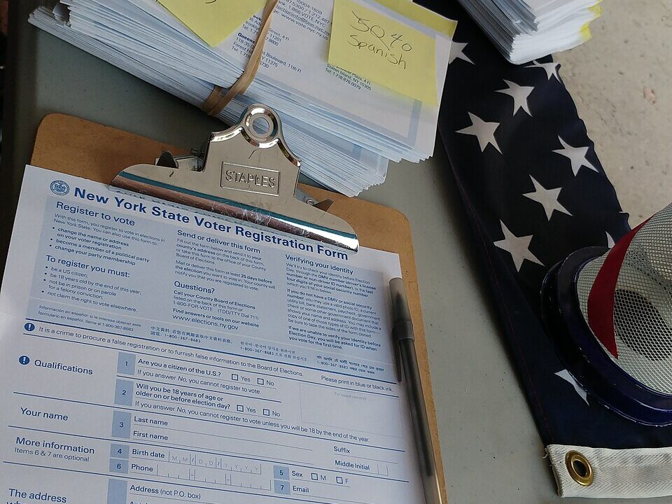 Voter registration forms and clipboard on a table with an American flag