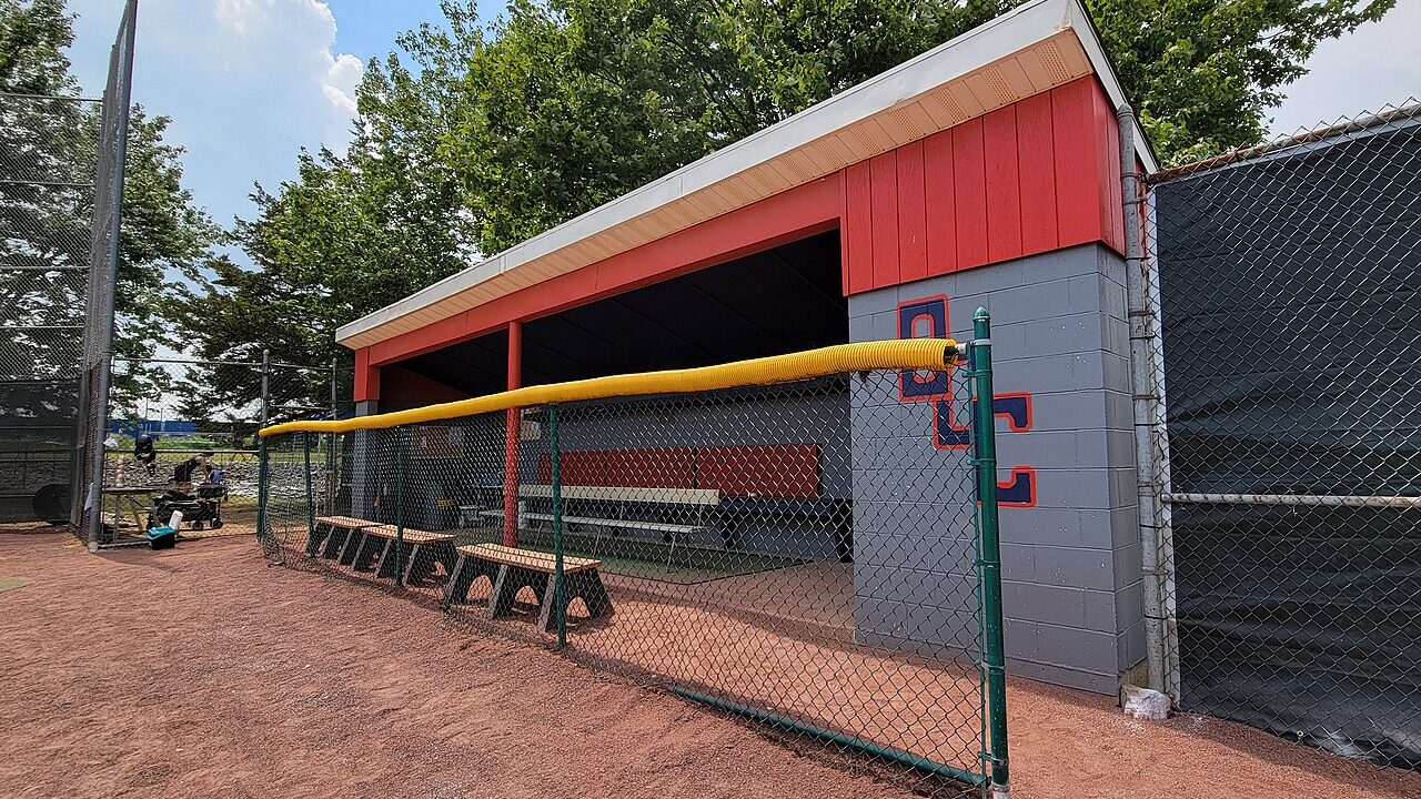 Empty baseball dugout with benches behind a chain-link fence