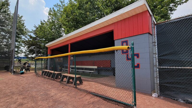 Empty baseball dugout with benches behind a chain-link fence