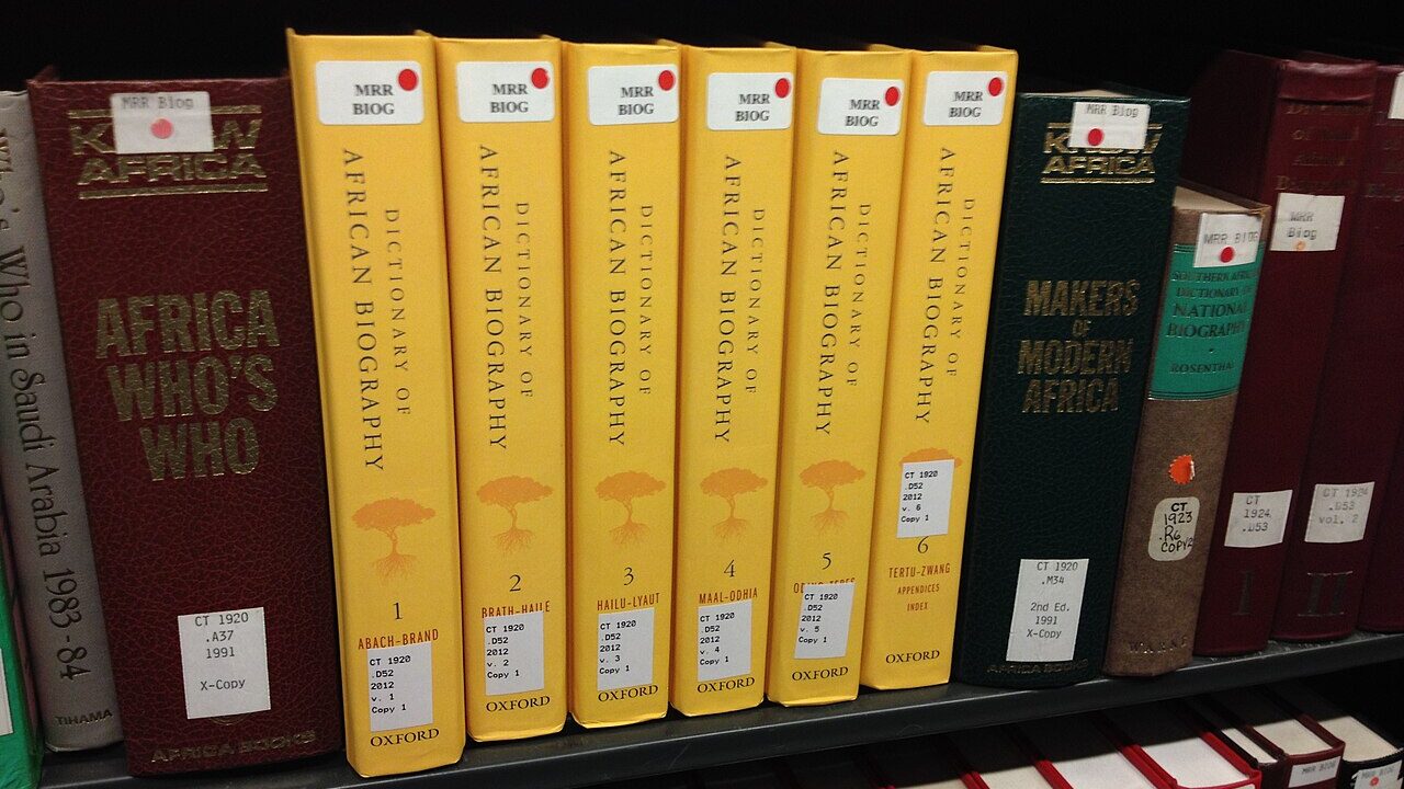 Shelves of hardback reference books with yellow and red spines in a library