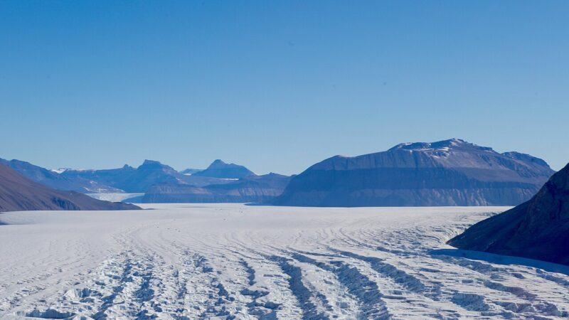 Vast white ice field stretching towards mountains under a clear blue sky in Antarctica