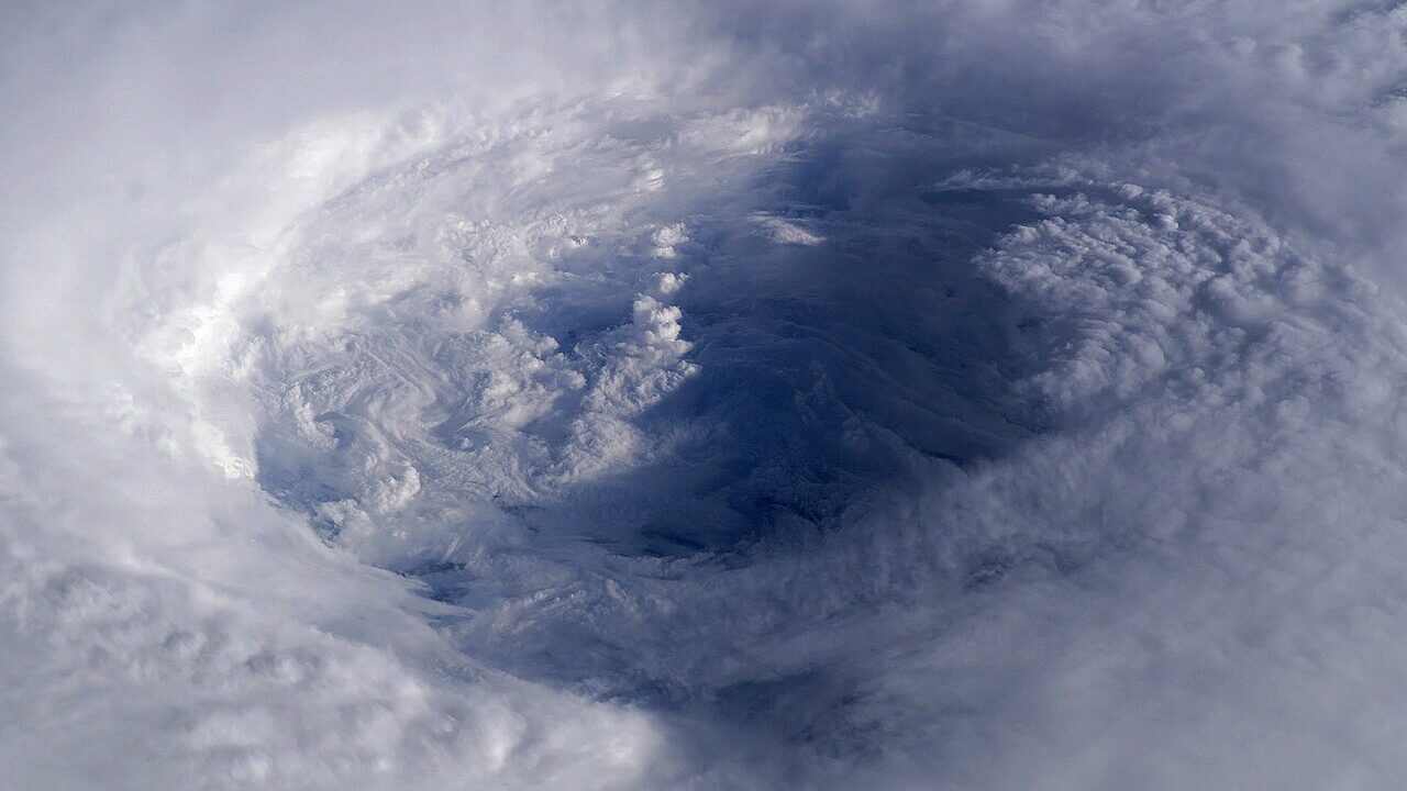 Swirling white cloud systems of a storm seen from orbit above Earth