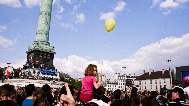Crowd gathered in a Paris square under a blue sky